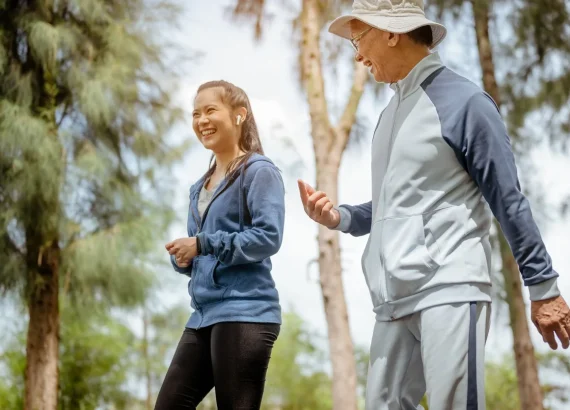 A woman and grandfather are walking jogging on the street at the park. Grandfather talk about the story of past life experiences. Healthy and lifestyle concept