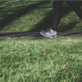 a person walking on a grassy path with fallen leaves