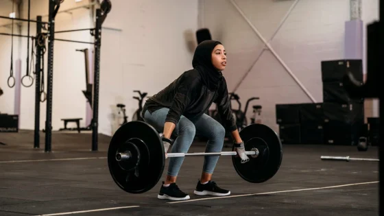 woman in hijab performing strength training deadlift at gym