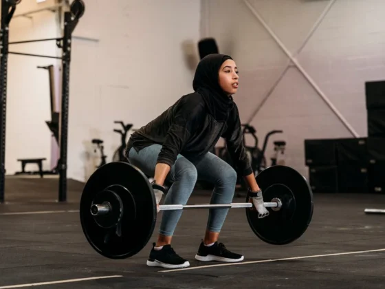 woman in hijab performing strength training deadlift at gym