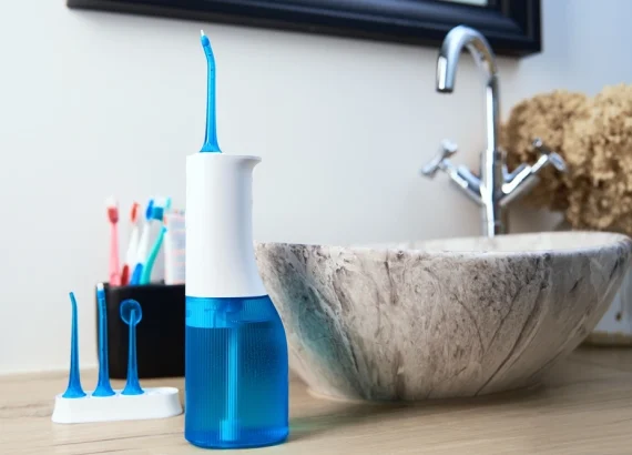 Water-flosser-with-tips-on-a-bathroom-counter-next-to-a-modern-sink
