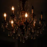 Dimly lit vintage chandelier with half the bulbs dark, others flickering