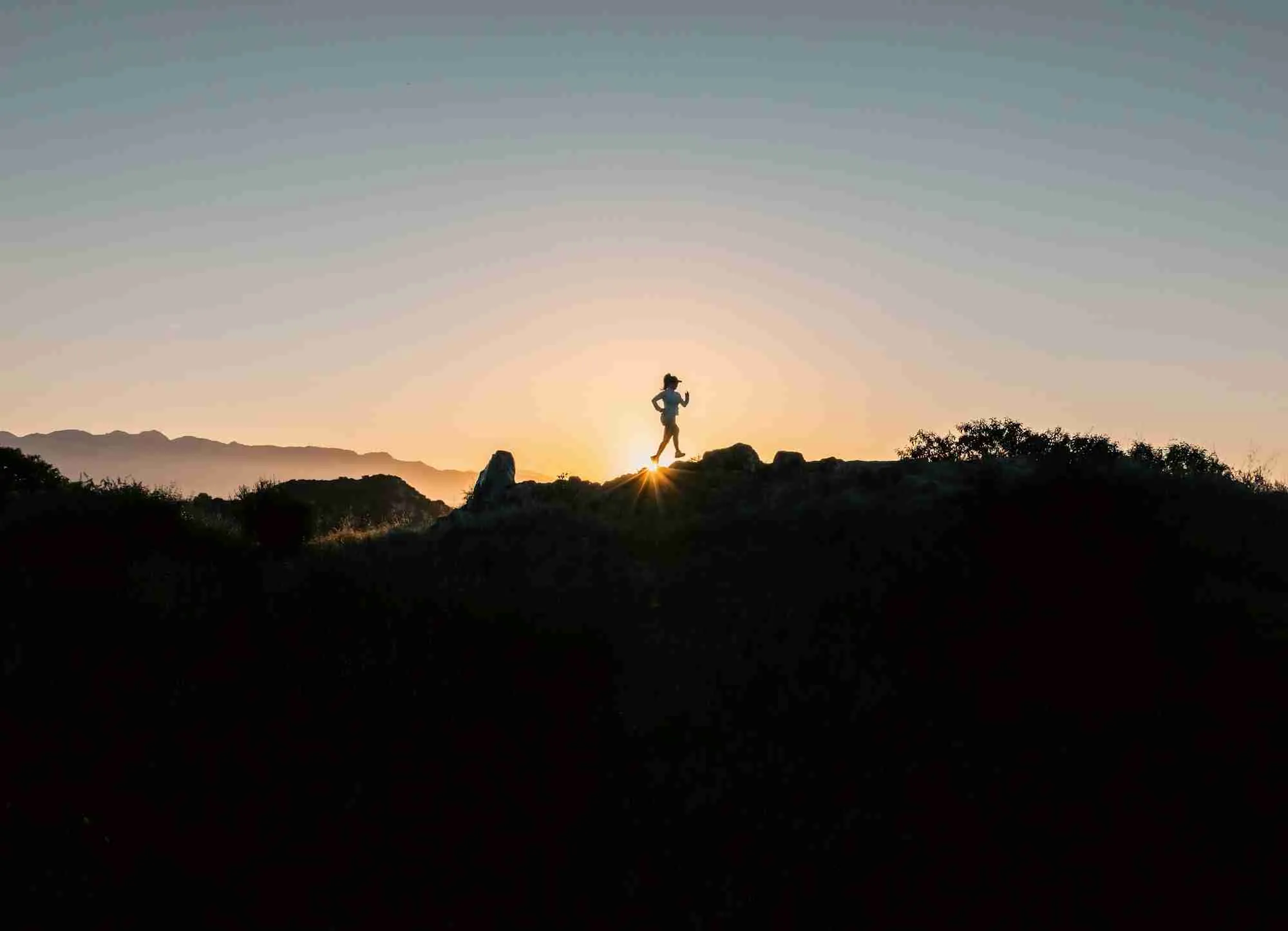 Silhouette of a runner on a ridge at sunset