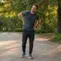 Man with lower back pain pausing on a park path